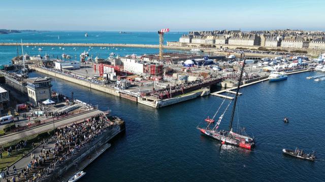 This aerial photograph shows skipper Jeremy Beyou sailing his Imoca Charal through the Naye lock of Saint-Malo's harbour, to moor off the coast of Saint-Malo northwestern France on October 31, 2026 on the eve of the start of the Route du Rhum solo sailing race from Saint-Malo, to Pointe-a-Pitre in the French overseas island of Guadeloupe. (Photo by LOU BENOIST / AFP)
