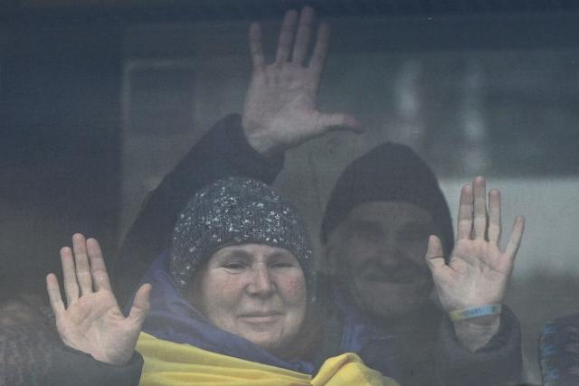 Residents evacuated from the Russian-controlled city of Oleshky during a humanitarian mission gesture next to a window sitting in a bus upon arriving at an undisclosed location in Ukraine on October 31, 2026, amid the Russian invasion of Ukraine. Residents of the Russian-controlled city of Oleshky, ravaged by years of war, arrived in Ukraine on October 31, 2026 after being evacuated via Belarus during a rare truce. (Photo by Genya Savilov / AFP)