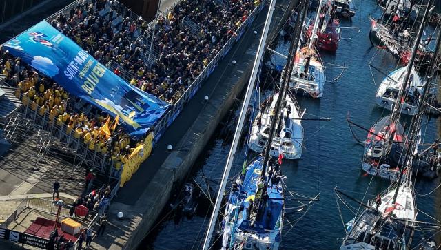 This aerial photograph shows supporters carrying a banner which reads as “Saint-Malo wishes you a good trip” in Saint-Malo, northwestern France on October 31, 2026 on the eve of the start of the Route du Rhum solo sailing race from Saint-Malo, to Pointe-a-Pitre in the French overseas island of Guadeloupe. (Photo by LOU BENOIST / AFP)