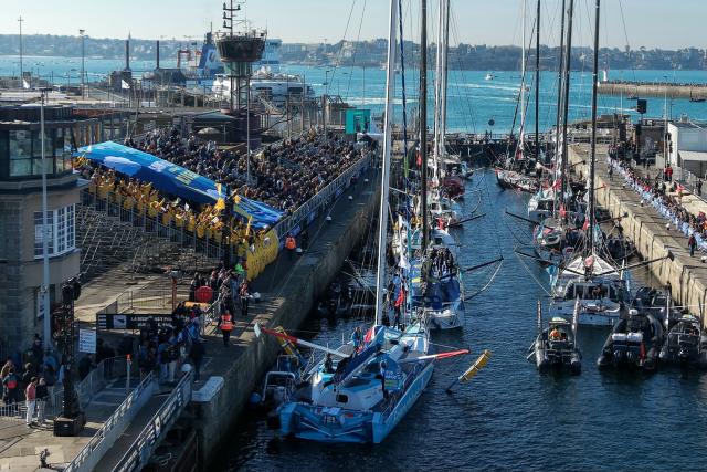 This aerial photograph shows supporters carrying a banner which reads as “Saint-Malo wishes you a good trip” in Saint-Malo, northwestern France on October 31, 2026 on the eve of the start of the Route du Rhum solo sailing race from Saint-Malo, to Pointe-a-Pitre in the French overseas island of Guadeloupe. (Photo by LOU BENOIST / AFP)