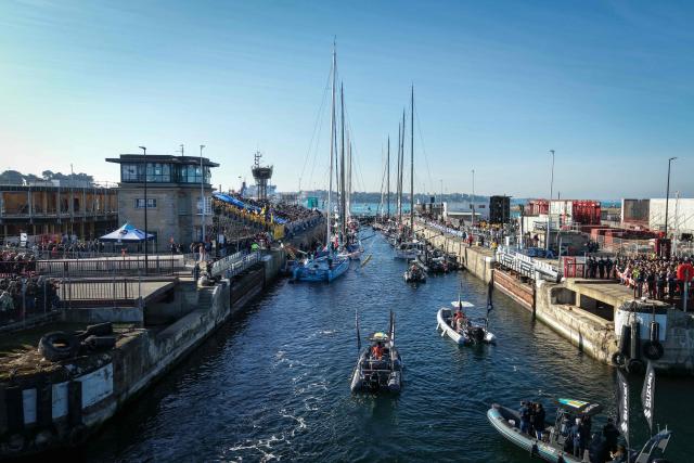 This aerial photograph shows  Imoca class leaving the harbour of Saint-Malo, northwestern France on October 31, 2026 on the eve of the start of the Route du Rhum solo sailing race from Saint-Malo, to Pointe-a-Pitre in the French overseas island of Guadeloupe. (Photo by LOU BENOIST / AFP)