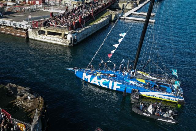 This aerial photograph shows British sailor Sam Goodchild aboard his "Macif Sante Prevoyance" IMOCA Class leaving the harbour of Saint-Malo, northwestern France on October 31, 2026 on the eve of the start of the Route du Rhum solo sailing race from Saint-Malo, to Pointe-a-Pitre in the French overseas island of Guadeloupe. (Photo by LOU BENOIST / AFP)