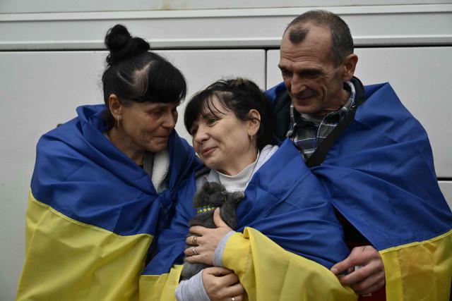 Residents and their cat evacuated from the Russian-controlled city of Oleshky during a humanitarian mission react upon arriving at an undisclosed location in Ukraine on October 31, 2026, amid the Russian invasion of Ukraine. Residents of the Russian-controlled city of Oleshky, ravaged by years of war, arrived in Ukraine on October 31, 2026 after being evacuated via Belarus during a rare truce brokered by US First Lady Melania Trump. (Photo by Genya SAVILOV / AFP)