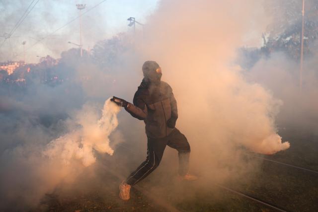 A protester launches a tear gas canister towards French police officers 
at the end of a protest march during nationwide demonstrations over the rising cost of living and inequality organised by Yellow Vest movement, labour unions and high school and university students, in Paris on October 31, 2026.. "Exceptional" security deployment with 70,000 police officers and gendarmes mobilized and an alarmist tone: for Act III of the protests against the high cost of living, right in the middle of Halloween festivities, the authorities fear a repeat of the October 17 nightmare. France has been rocked by widespread anger over the rising cost of living and inequality. (Photo by Sameer AL-DOUMY / AFP)