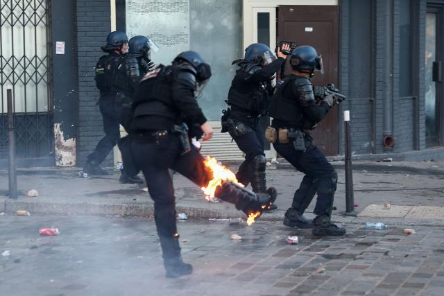 A French Gendarme who is partly burning tries to extinguish the fire in a street as facing protesters at the end of a protest march during nationwide demonstrations over the rising cost of living and inequality organised by Yellow Vest movement, labour unions and high school and university students, in Paris on October 31, 2026. "Exceptional" security deployment with 70,000 police officers and gendarmes mobilized and an alarmist tone: for Act III of the protests against the high cost of living, right in the middle of Halloween festivities, the authorities fear a repeat of the October 17 nightmare. France has been rocked by widespread anger over the rising cost of living and inequality. (Photo by Sameer AL-DOUMY / AFP)