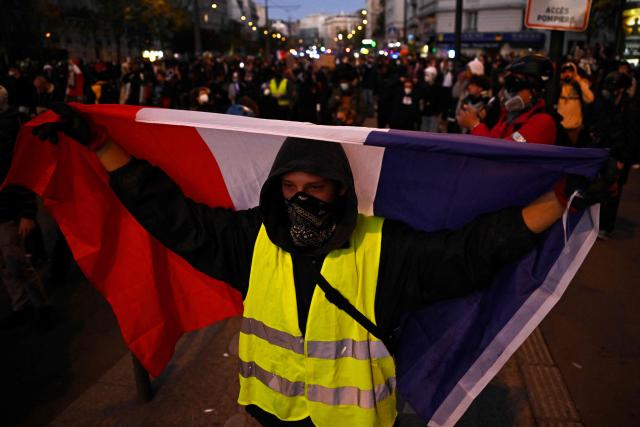 A protester with a yellow vest holds a French flag during nationwide demonstrations over the rising cost of living and inequality organised by Yellow Vest movement, labour unions and high school and university students, in Paris on October 31, 2026. "Exceptional" security deployment with 70,000 police officers and gendarmes mobilized and an alarmist tone: for Act III of the protests against the high cost of living, right in the middle of Halloween festivities, the authorities fear a repeat of the October 17 nightmare. France has been rocked by widespread anger over the rising cost of living and inequality. (Photo by JULIEN DE ROSA / AFP)
