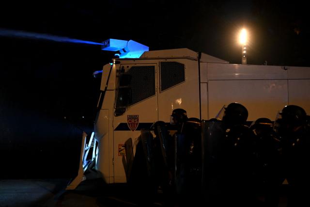 French Republican Security Corps (CRS - Compagnies Republicaines de Securite) police officers stand next to a water cannon vehicle spraying water during nationwide demonstrations over the rising cost of living and inequality organised by Yellow Vest movement, labour unions and high school and university students, in Montpellier, southern France on October 31, 2026. "Exceptional" security deployment with 70,000 police officers and gendarmes mobilized and an alarmist tone: for Act III of the protests against the high cost of living, right in the middle of Halloween festivities, the authorities fear a repeat of the October 17 nightmare. France has been rocked by widespread anger over the rising cost of living and inequality. (Photo by Sylvain THOMAS / AFP)