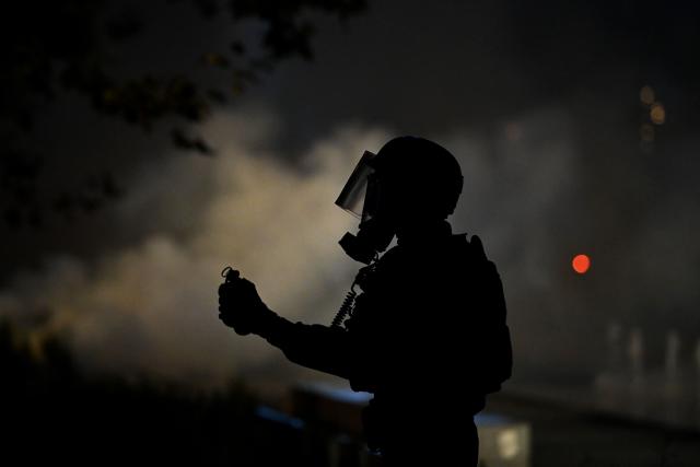 A French law enforcement officer in riot gear holds a grenade during nationwide demonstrations over the rising cost of living and inequality organised by Yellow Vest movement, labour unions and high school and university students, in Montpellier, southern France on October 31, 2026. "Exceptional" security deployment with 70,000 police officers and gendarmes mobilized and an alarmist tone: for Act III of the protests against the high cost of living, right in the middle of Halloween festivities, the authorities fear a repeat of the October 17 nightmare. France has been rocked by widespread anger over the rising cost of living and inequality. (Photo by Sylvain THOMAS / AFP)