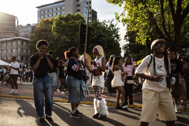 Two attendees chat as another touches up her lipstick during Johannesburg Pride in Sandton, on October 31, 2026. People filled the streets of Sandton City in Johannesburg for Africa’s oldest Pride event, marking 37 years of protest, courage and celebration. Launched in 1990, before South Africa became a democracy, Johannesburg Pride has grown from an act of defiance under apartheid into a continental movement for equality. (Photo by ILARIA FINIZIO / AFP)