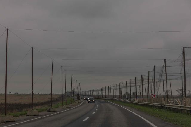 This photograph shows anti-drone nets over a road with droven cars during a temporary ceasefire in the southern Kherson region, in the Kherson region, southern Ukraine, on October 31, 2026, amid the Russian invasion of Ukraine. The respite from a fragile ceasefire in Oleshky, a Russian-occupied town in southern Ukraine ravaged by food and medicine shortages, to pave the way for evacuations and humanitarian aid deliveries and due to end on November 1 evening, has also given residents in the major southern Ukrainian city of Kherson relief from daily drone attacks. The truce has held despite unabated attacks elsewhere in Ukraine. (Photo by Roman PILIPEY / AFP)