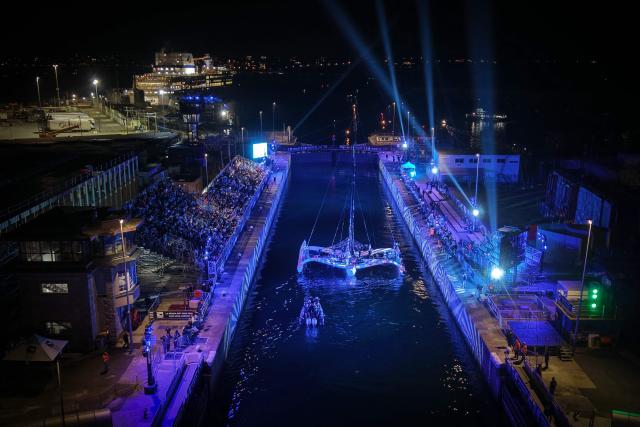 This aerial photograph shows Sodebo Ocean Fifty class leaving at night the harbour of Saint-Malo, western France, on October 31, 2026, ahead of the start of the 13th Route du Rhum - Destination Guadeloupe solo sailing race from Saint-Malo, western France to Pointe-a-Pitre in the French overseas island of Guadeloupe. (Photo by LOU BENOIST / AFP)