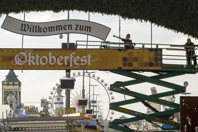 FILED - 18 September 2024, Bavaria, Munich: Workers stand on a lifting platform during construction work on the Oktoberfest grounds at the main entrance. Photo: Peter Kneffel/dpa