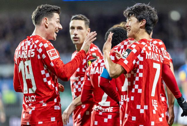 24 November 2024, Schleswig-Holstein, Kiel: Mainz's Jae-Sung Lee (R) celebrates scoring his side's third goal with teammate Anthony Caci during the German Bundesliga soccer match between Holstein Kiel and FSV Mainz 05 at Holstein Stadium. Photo: Axel Heimken/dpa - WICHTIGER HINWEIS: Gemäß den Vorgaben der DFL Deutsche Fußball Liga bzw. des DFB Deutscher Fußball-Bund ist es untersagt, in dem Stadion und/oder vom Spiel angefertigte Fotoaufnahmen in Form von Sequenzbildern und/oder videoähnlichen Fotostrecken zu verwerten bzw. verwerten zu lassen.