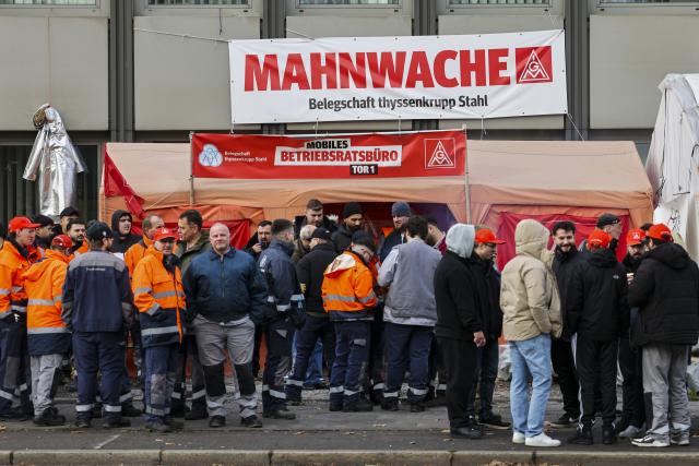 26 November 2024, North Rhine-Westphalia, Duisburg: Employees of Thyssenkrupp Steel stand in front of the factory gate at a vigil. Photo: Christoph Reichwein/dpa