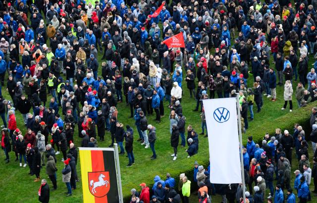 02 December 2024, Lower Saxony, Wolfsburg: Volkswagen employees stand at a strike rally on the grounds of the VW main plant in Wolfsburg. IG Metall calls for warning strikes at several German Volkswagen sites over wage cuts, lay-offs. Photo: Julian Stratenschulte/dpa Pool/dpa