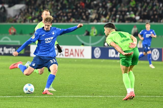 04 December 2024, Lower Saxony, Wolfsburg: Hoffenheim's Max Moerstedt (L) shoots at goal against Wolfsburg's Konstantinos Koulierakis during the German DFB Cup round of 16 soccer match between VfL Wolfsburg and TSG 1899 Hoffenheim at the Volkswagen Arena Photo: Swen Pförtner/dpa - WICHTIGER HINWEIS: Gemäß den Vorgaben der DFL Deutsche Fußball Liga bzw. des DFB Deutscher Fußball-Bund ist es untersagt, in dem Stadion und/oder vom Spiel angefertigte Fotoaufnahmen in Form von Sequenzbildern und/oder videoähnlichen Fotostrecken zu verwerten bzw. verwerten zu lassen.