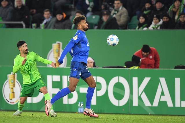 04 December 2024, Lower Saxony, Wolfsburg: Hoffenheim's Kevin Akpoguma (R) and Wolfsburg's Mohamed Amoura battle for the ball during the German DFB Cup round of 16 soccer match between VfL Wolfsburg and TSG 1899 Hoffenheim at the Volkswagen Arena Photo: Swen Pförtner/dpa - WICHTIGER HINWEIS: Gemäß den Vorgaben der DFL Deutsche Fußball Liga bzw. des DFB Deutscher Fußball-Bund ist es untersagt, in dem Stadion und/oder vom Spiel angefertigte Fotoaufnahmen in Form von Sequenzbildern und/oder videoähnlichen Fotostrecken zu verwerten bzw. verwerten zu lassen.