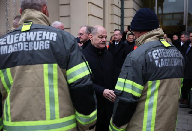 21 December 2024, Saxony-Anhalt, Magdeburg: German Chancellor Olaf Scholz (C) visits the scene of the fatal attack at Magdeburg's Christmas market and expresses gratitude to the fire department. The previous evening, a driver rammed a car into a crowd at the market, causing multiple fatalities and injuries. Photo: Jan Woitas/dpa