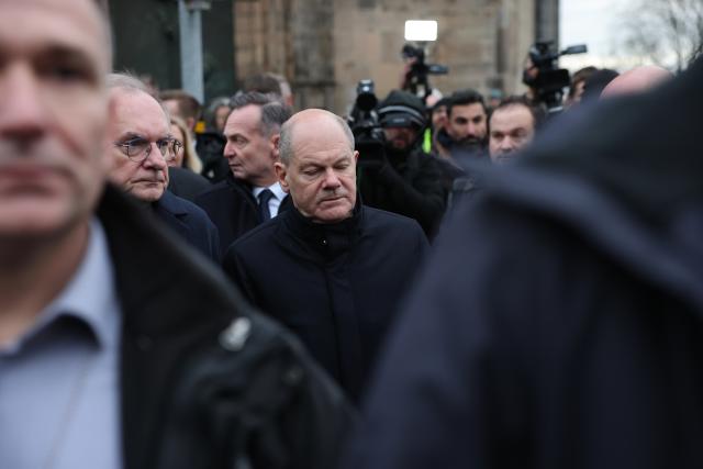 21 December 2024, Saxony-Anhalt, Magdeburg: Federal Chancellor Olaf Scholz (C) and Reiner Haseloff (L), Minister President of Saxony-Anhalt, visit the site of the fatal attack at the Christmas market. The evening before, a driver drove into a crowd at the Magdeburg Christmas market, resulting in several fatalities and injuries. Photo: Jan Woitas/dpa