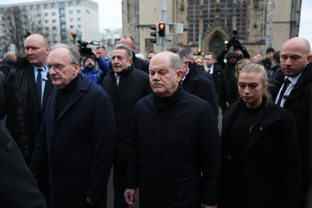 21 December 2024, Saxony-Anhalt, Magdeburg: Germany's Chancellor Olaf Scholz (C) and Reiner Haseloff (Center L), Minister President of Saxony-Anhalt, visit the site of the fatal attack at Magdeburg's Christmas market. The previous evening, a driver drove into a crowd at the market, resulting in several fatalities and injuries. Photo: Jan Woitas/dpa