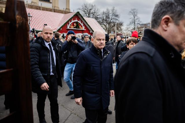 21 December 2024, Saxony-Anhalt, Magdeburg: Germany's Chancellor Olaf Scholz (C) departs from the Christmas market in Magdeburg after making a statement. The previous evening, a driver drove into a group of people at the market, resulting in several fatalities and injuries. Photo: Christoph Soeder/dpa