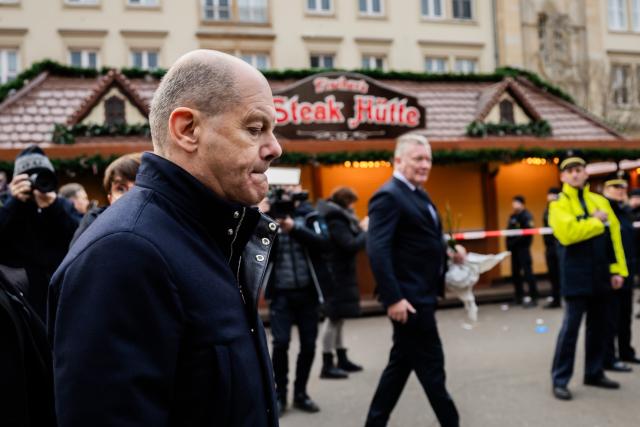 21 December 2024, Saxony-Anhalt, Magdeburg: Germany's Chancellor Olaf Scholz (C) departs from the Christmas market in Magdeburg after delivering a statement. The previous evening, a driver drove into a group of people at the market, resulting in fatalities and injuries. Photo: Christoph Soeder/dpa