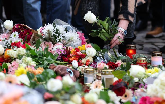 21 December 2024, Saxony-Anhalt, Magdeburg: A woman lays flowers at the official memorial site at St. John's Church in Magdeburg. The previous evening, a driver rammed into a group of people at Magdeburg's Christmas market. Several people were killed and injured in the attack. Photo: Jan Woitas/dpa