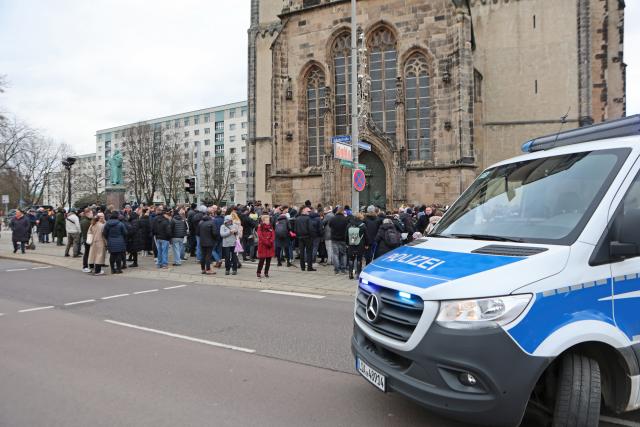 21 December 2024, Saxony-Anhalt, Magdeburg: A police emergency vehicle guards the area, as people lay flowers and candles at the official place of mourning in front of St. John's Church in Magdeburg. The previous evening, a driver rammed into a group of people at Magdeburg's Christmas market. Several people were killed and injured in the attack. Photo: Matthias Bein/dpa