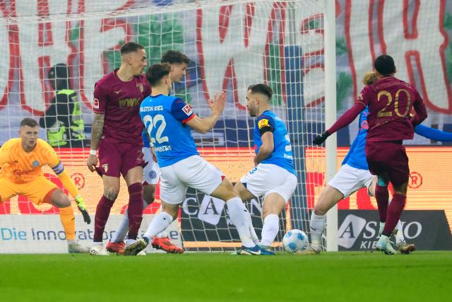 21 December 2024, Schleswig-Holstein, Kiel: Augsburg's Alexis Claude-Maurice (R) scores his side's first goal during the German Bundesliga soccer match between Holstein Kiel and FC Augsburg at Holstein Stadium. Photo: Frank Molter/dpa - IMPORTANT NOTICE: DFL and DFB regulations prohibit any use of photographs as image sequences and/or quasi-video.