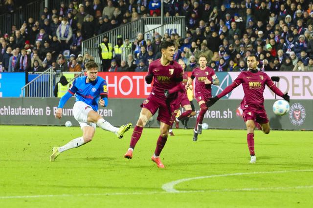 21 December 2024, Schleswig-Holstein, Kiel: Kiel's Phil Harres (L) scores his side's third goal during the German Bundesliga soccer match between Holstein Kiel and FC Augsburg at Holstein Stadium. Photo: Frank Molter/dpa - IMPORTANT NOTICE: DFL and DFB regulations prohibit any use of photographs as image sequences and/or quasi-video.