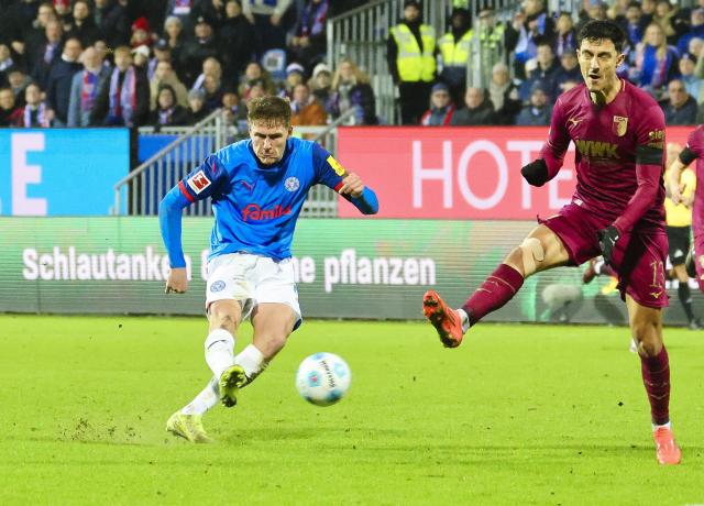 21 December 2024, Schleswig-Holstein, Kiel: Kiel's Phil Harres (L) scores his side's third goal during the German Bundesliga soccer match between Holstein Kiel and FC Augsburg at Holstein Stadium. Photo: Frank Molter/dpa - IMPORTANT NOTICE: DFL and DFB regulations prohibit any use of photographs as image sequences and/or quasi-video.