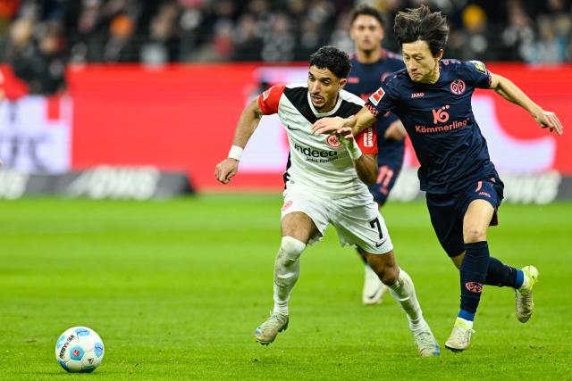 21 December 2024, Hesse, Frankfurt_Main: Frankfurt's Omar Marmoush (L) and Mainz's Jae-Sung Lee battle for the ball, during the German Bundesliga soccer match between Eintracht Frankfurt and FSV Mainz 05 at the Deutsche Bank Park. Photo: Uwe Anspach/dpa - IMPORTANT NOTE: In accordance with the regulations of the DFL German Football League and the DFB German Football Association, it is prohibited to utilize or have utilized photographs taken in the stadium and/or of the match in the form of sequential images and/or video-like photo series.