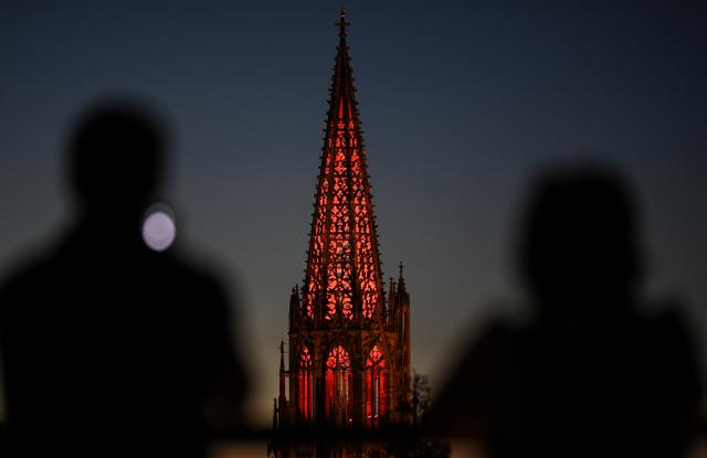 FILED - 13 October 2018, Baden-Wuerttemberg, Freiburg: People look at the illuminated tower of the Freiburg Cathedral. Photo: Patrick Seeger/dpa