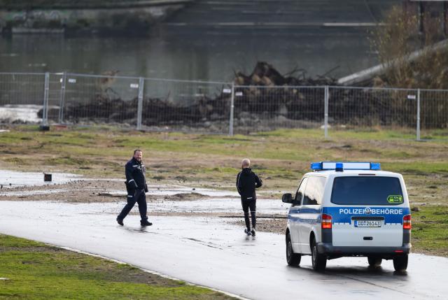 08 January 2025, Saxony, Dresden: A policeman prevents a jogger on the Koenigsufer from continuing his run. A bomb has been found during demolition work on the partially collapsed Carola Bridge in Dresden. Photo: Robert Michael/dpa