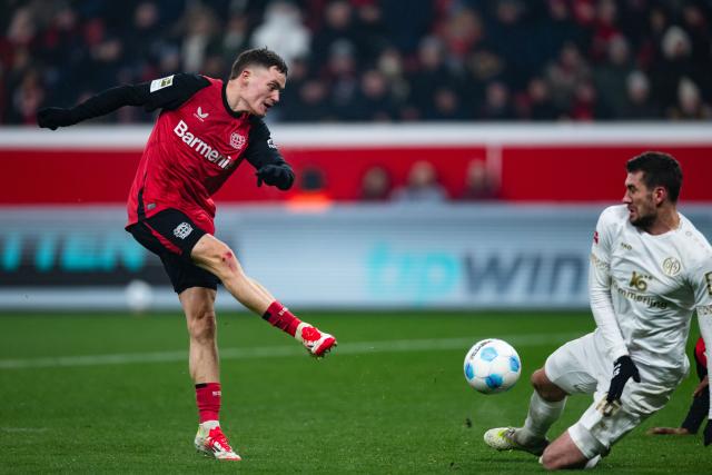 14 January 2025, North Rhine-Westphalia, Leverkusen: Leverkusen's Florian Wirtz (L) shoots at Mainz's Stefan Bell during the German Bundesliga soccer match between Bayer Leverkusen and Mainz 05 at BayArena. Photo: Marius Becker/dpa - IMPORTANT NOTICE: DFL and DFB regulations prohibit any use of photographs as image sequences and/or quasi-video.