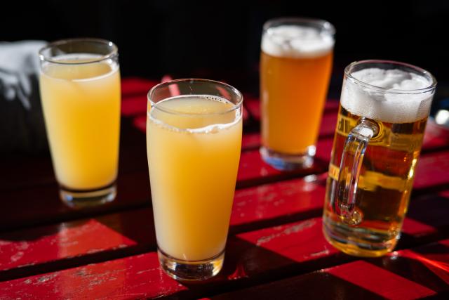 FILED - 28 July 2024, Berlin: Two glasses of apple juice spritzer (L) and various beers (R) are placed on a table in a beer garden. Photo: Sebastian Gollnow/dpa