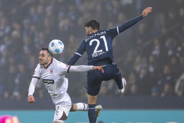 15 January 2025, Bochum: St. Pauli's Manolis Saliakas (L) and Bochum's Gerrit Holtmann battle for the ball during the German Bundesliga soccer match between VfL Bochum 1848 and FC St. Pauli at Vonovia Ruhrstadion. Photo: David Inderlied/dpa - IMPORTANT NOTICE: DFL and DFB regulations prohibit any use of photographs as image sequences and/or quasi-video.