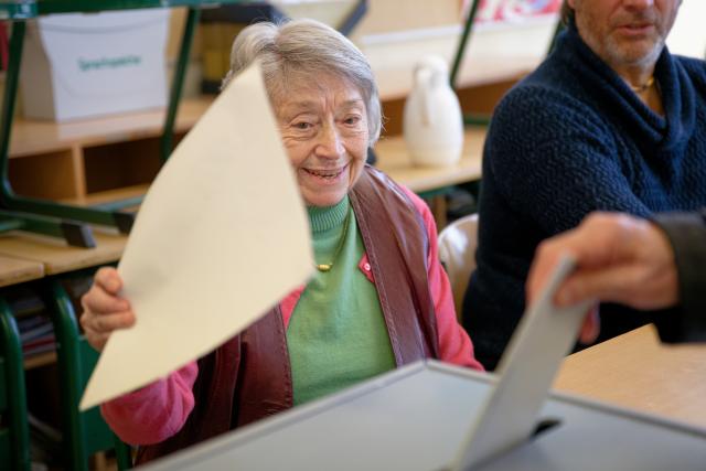 23 February 2025, North Rhine-Westphalia, Cologne: Cologne's oldest poll worker, Lydia Mors-Plattesat who is a 100 years old, sits at the ballot box of her polling station during the German Federal election. Photo: Henning Kaiser/dpa