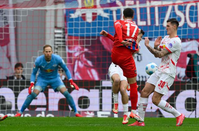 23 February 2025, Saxony, Leipzig: Heidenheim's Mathias Honsak (2nd R) scores his side's first goal past Leipzig goalkeeper Peter Gulacsi during the German Bundesliga soccer match between RB Leipzig and 1. FC Heidenheim at the Red Bull Arena. Photo: Hendrik Schmidt/dpa - IMPORTANT NOTE: In accordance with the regulations of the DFL German Football League and the DFB German Football Association, it is prohibited to utilize or have utilized photographs taken in the stadium and/or of the match in the form of sequential images and/or video-like photo series.