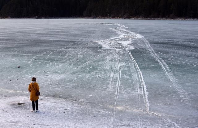 06 March 2025, Bavaria, Grainau: A woman stands on the shore of the frozen Lake Eibsee near the spot where several people broke through the ice in the afternoon. Photo: Karl-Josef Hildenbrand/dpa