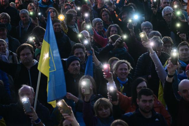 09 March 2025, Berlin: Participants hold up their smartphones during the demonstration "Stand with Ukraine" in solidarity with Ukraine, in front of the Brandenburg Gate. Photo: Sebastian Christoph Gollnow/dpa