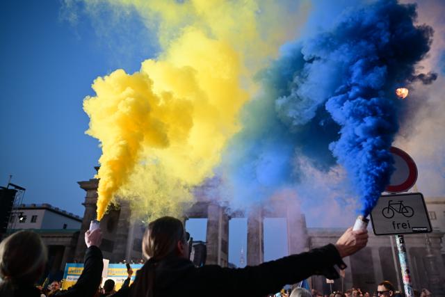 09 March 2025, Berlin: Participants hold up smoke flares in the national colors of Ukraine, during the demonstration "Stand with Ukraine" in solidarity with Ukraine, in front of the Brandenburg Gate. Photo: Sebastian Christoph Gollnow/dpa