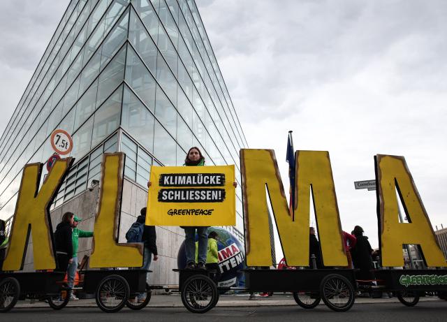 13 March 2025, Berlin: A demonstrator holds a banner reading "Close the climate gap!" as Fridays for Future and Greenpeace activists protest against the new special fund in front of the Christian Democratic Union of Germany headquarters building Konrad Adenauer House in Berlin. Photo: Hannes P. Albert/dpa