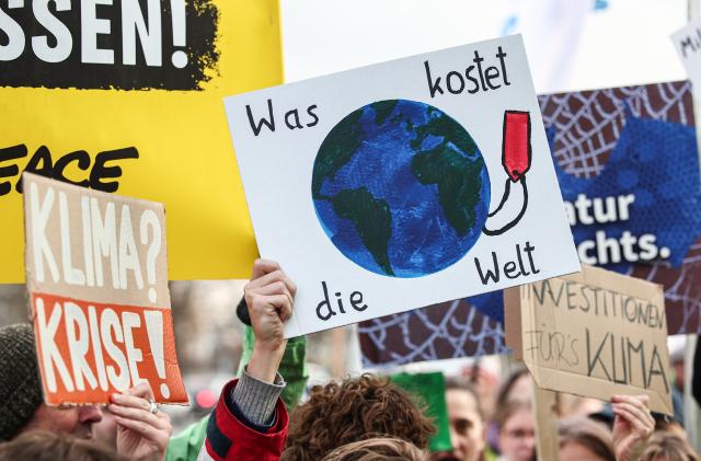 13 March 2025, Berlin: Signs with the words "Climate? Crisis!" and "What does the world cost" are held by Fridays for Future and Greenpeace activists during a protest against the new special fund in front of the Christian Democratic Union of Germany headquarters building Konrad Adenauer House in Berlin. Photo: Hannes P. Albert/dpa