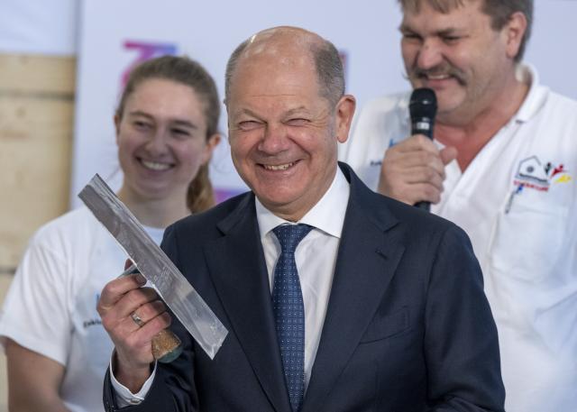 14 March 2025, Bavaria, Munich: Germany's Chancellor Olaf Scholz holds a trowel during a tour of the International Crafts Fair. Earlier, he attended the meeting of the presidents of Germany's four leading industry associations. Photo: Peter Kneffel/dpa