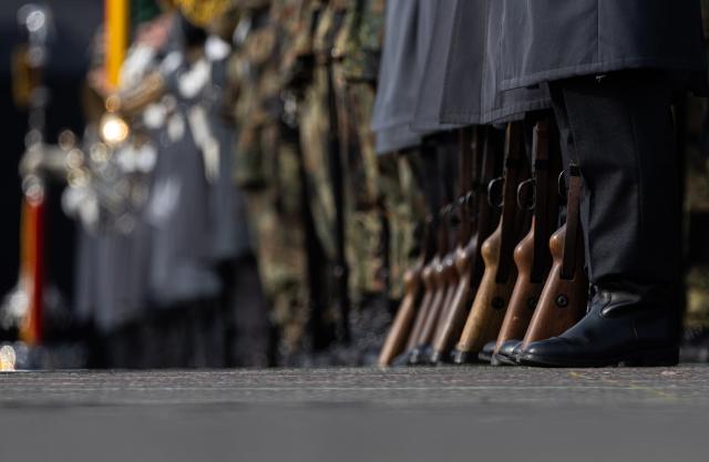 14 March 2025, Berlin: Soldiers from the Guard Battalion place their rifles beside them during the event as the army establishes a new homeland security division as its fourth major unit. Photo: Hannes P. Albert/dpa