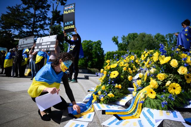 09 May 2025, Berlin: A woman places slips of paper bearing the names of Ukrainian soldiers who died during the liberation of Berlin next to wreaths in Ukrainian colors at the Soviet Memorial in Tiergarten. The memorial honors Soviet soldiers killed in the Second World War. While May 8 is marked as the end of the war in Europe, Victory Day is observed on May 9 in Russia and several former Soviet states. Photo: Bernd von Jutrczenka/dpa