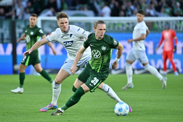 09 May 2025, Lower Saxony, Wolfsburg: Wolfsburg's Patrick Wimmer (R) and Hoffenheim's Marius Bulter battle for the ball during the German Bundesliga soccer match between VfL Wolfsburg and TSG 1899 Hoffenheim at the Volkswagen Arena. Photo: Swen Pförtner/dpa - IMPORTANT NOTE: In accordance with the regulations of the DFL German Football League and the DFB German Football Association, it is prohibited to utilize or have utilized photographs taken in the stadium and/or of the match in the form of sequential images and/or video-like photo series.