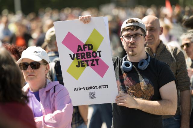 11 May 2025, Bavaria, Munich: A demonstrator holds a poster with the words "AfD ban now" during a rally as part of the nationwide day of action "No more excuses - ban the AfD now!", called by the alliance "Together against the right". Photo: Tobias Hase/dpa