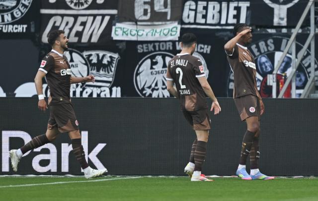 11 May 2025, Hesse, Frankfurt/Main: (R-L) St. Pauli's Morgan Guilavogui celebrates scoring his side's second goal with teammates Manolis Saliakas and Daniel Sinani during the German Bundesliga soccer match between Eintracht Frankfurt and FC St. Pauli at Deutsche Bank Park. Photo: Arne Dedert/dpa - WICHTIGER HINWEIS: Gemäß den Vorgaben der DFL Deutsche Fußball Liga bzw. des DFB Deutscher Fußball-Bund ist es untersagt, in dem Stadion und/oder vom Spiel angefertigte Fotoaufnahmen in Form von Sequenzbildern und/oder videoähnlichen Fotostrecken zu verwerten bzw. verwerten zu lassen.